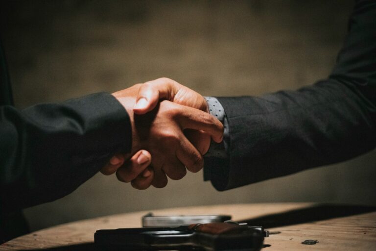 Two people shaking hands over a wooden table to close a deal