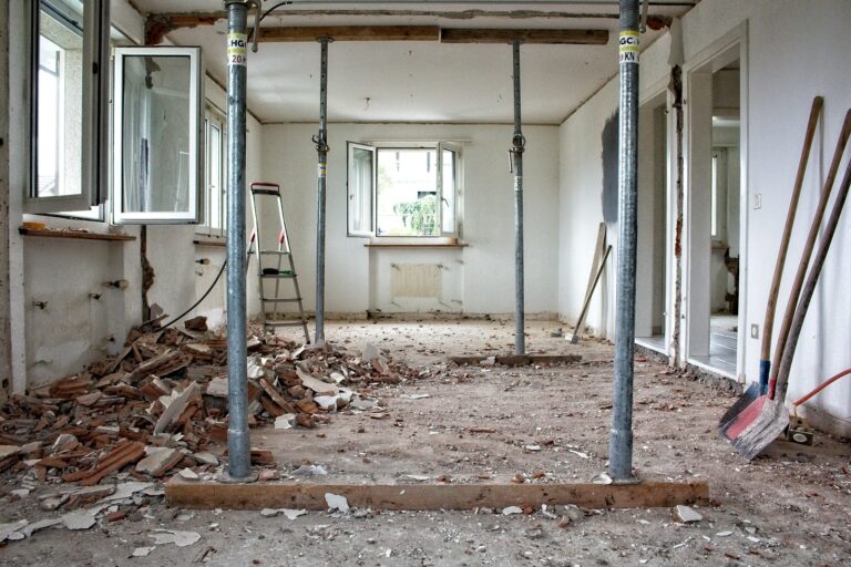 Room under renovation with support poles, debris, and construction tools on the floor