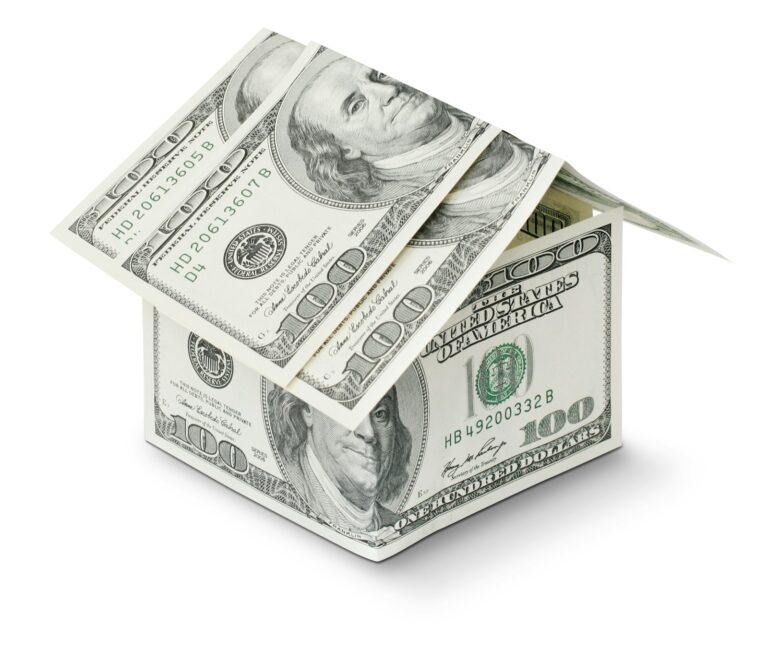 Small house shape made from folded one hundred dollar bills on a white background