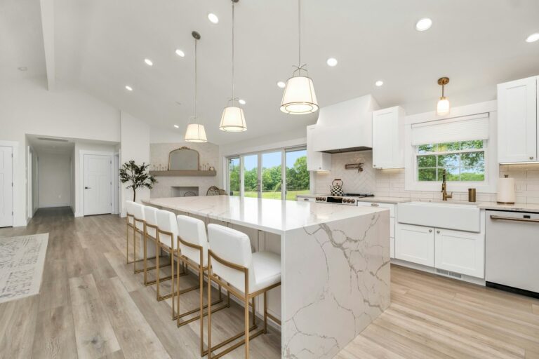 Bright renovated kitchen with a marble island and white cabinets