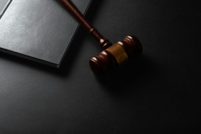 Judge's gavel resting beside a law book on a dark background