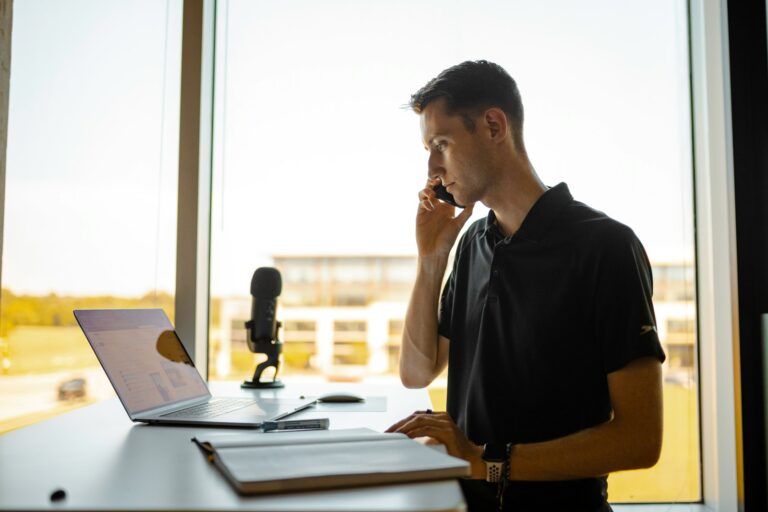 Person on the phone working at a computer in an office with a window view