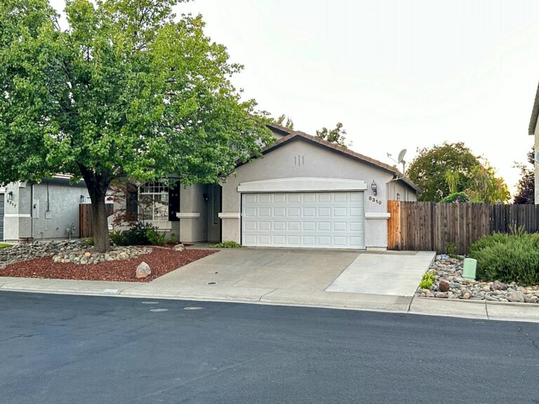 Suburban house with a white garage and a green tree