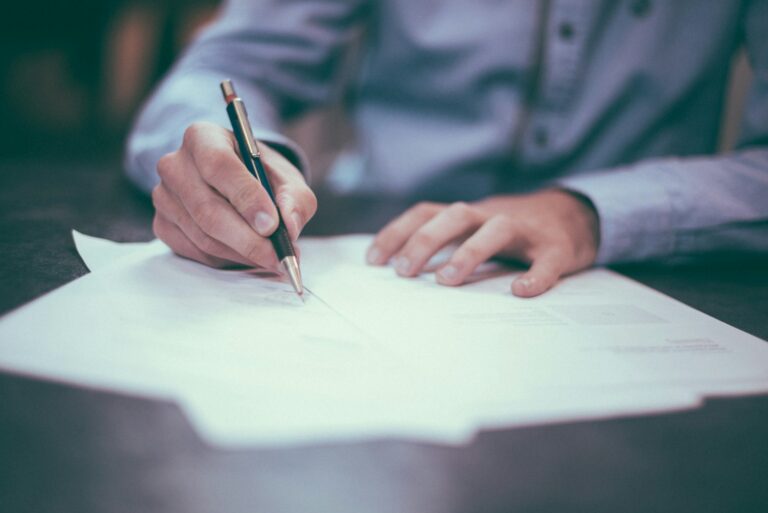 Close-up of a hand signing a contract document with a pen