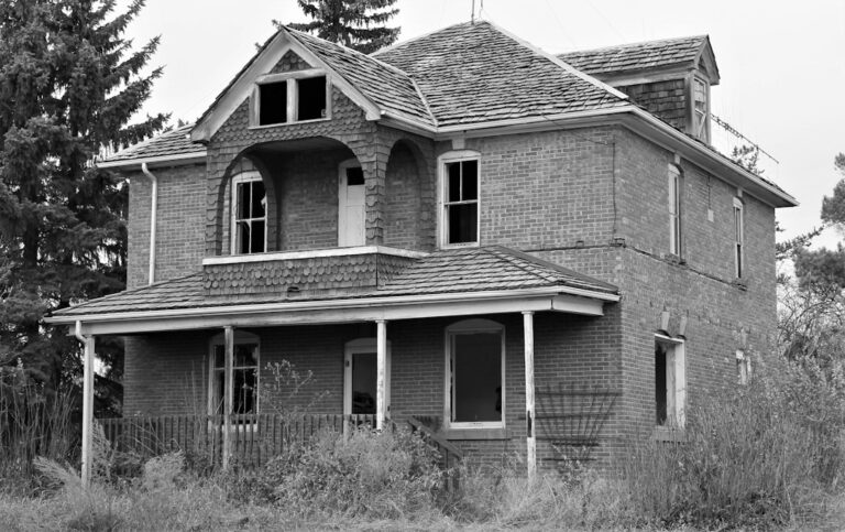 Distressed brick house with dark windows and a neglected yard, a common sign of a motivated seller