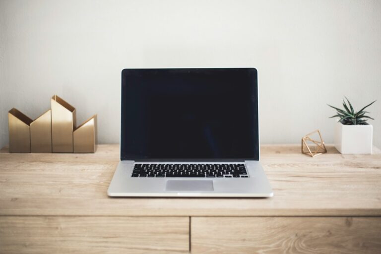 Laptop and notebook on a desk for comparing wholesaling courses, mentorship, and free videos
