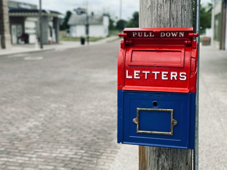 Red residential mailbox on a wooden post where direct mail from real estate wholesalers arrives
