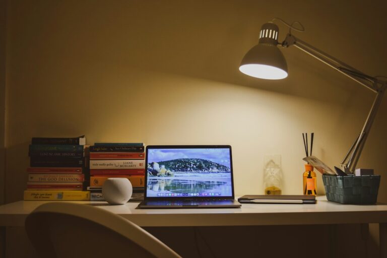 Laptop on a desk lit by a lamp for evening part-time wholesaling work