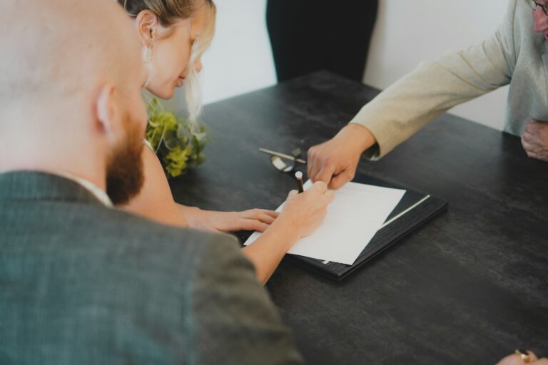 Couple signing a contract for deed at a desk to buy a home on installment terms