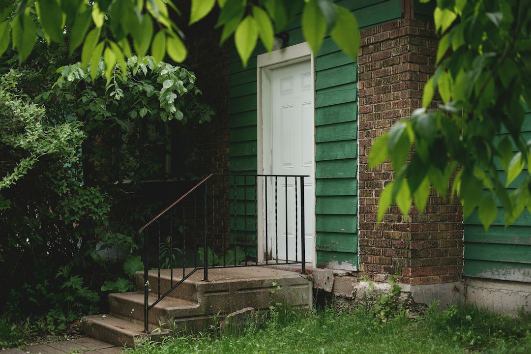 Green house with a white front door and lush yard, the kind of bank-owned home sold among REO properties