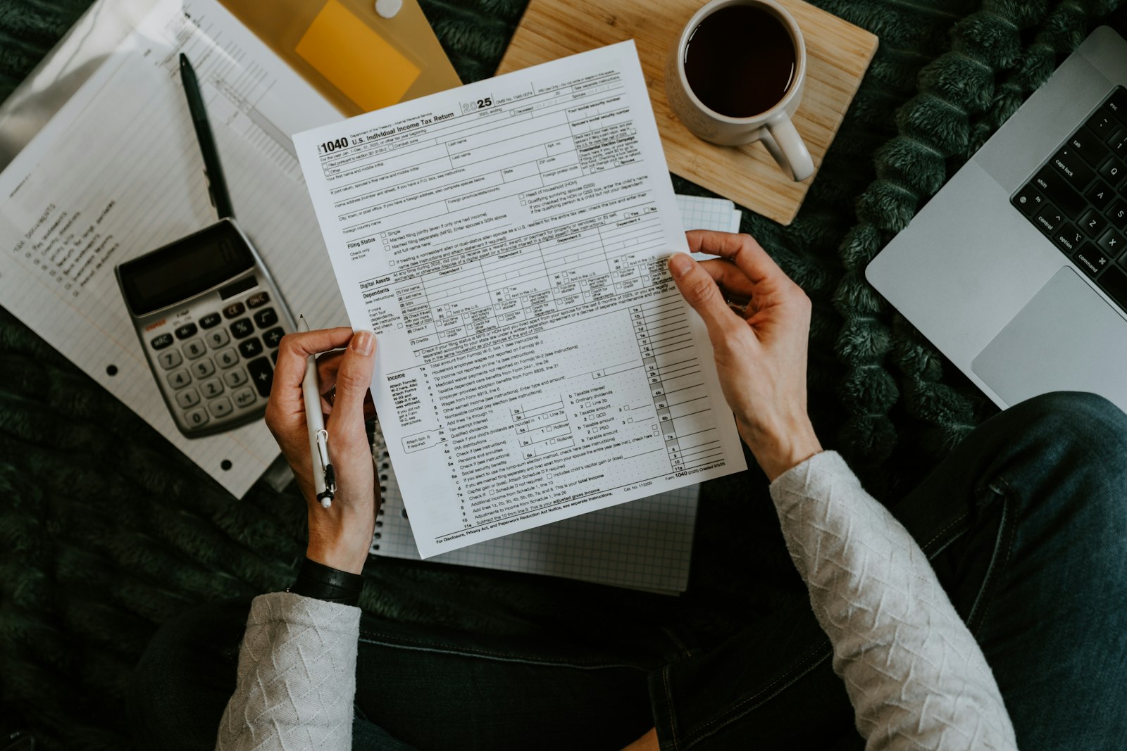Tax forms, a calculator and a laptop on a desk while estimating taxes on wholesale real estate income