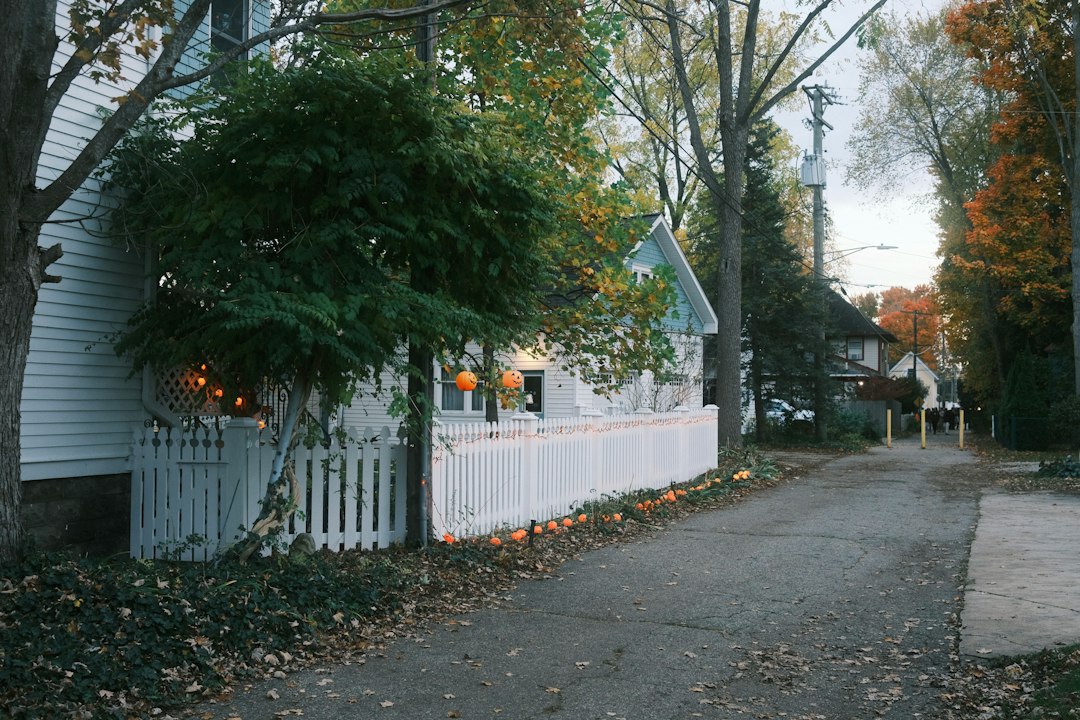 Tree-lined Michigan residential street with a white picket fence in autumn, illustrating the Michigan foreclosure timeline