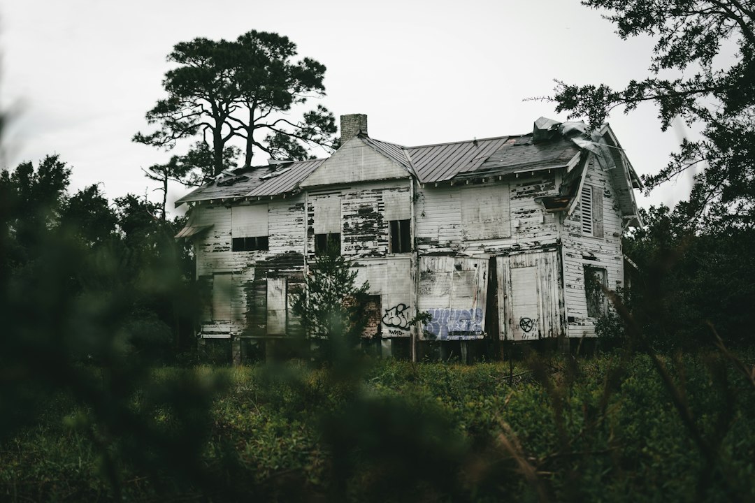 Vacant run-down house among trees, typical of zombie properties left empty during foreclosure