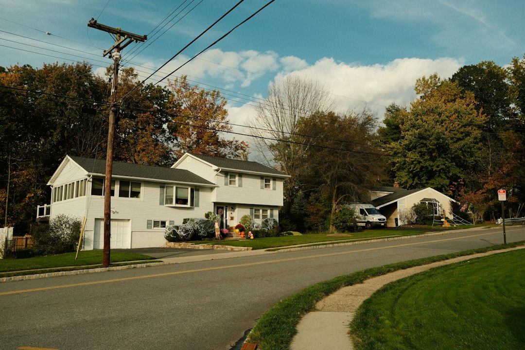 White two-story home on a quiet road, the kind of property that moves through the New Jersey foreclosure process